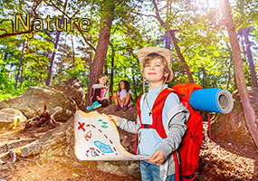 Colonies de vacances Nature et sports de pleine nature, un enfant souriant avec un chapeau d'aventurier porte un sac à dos et une carte de chasse au trésor dans la forêt